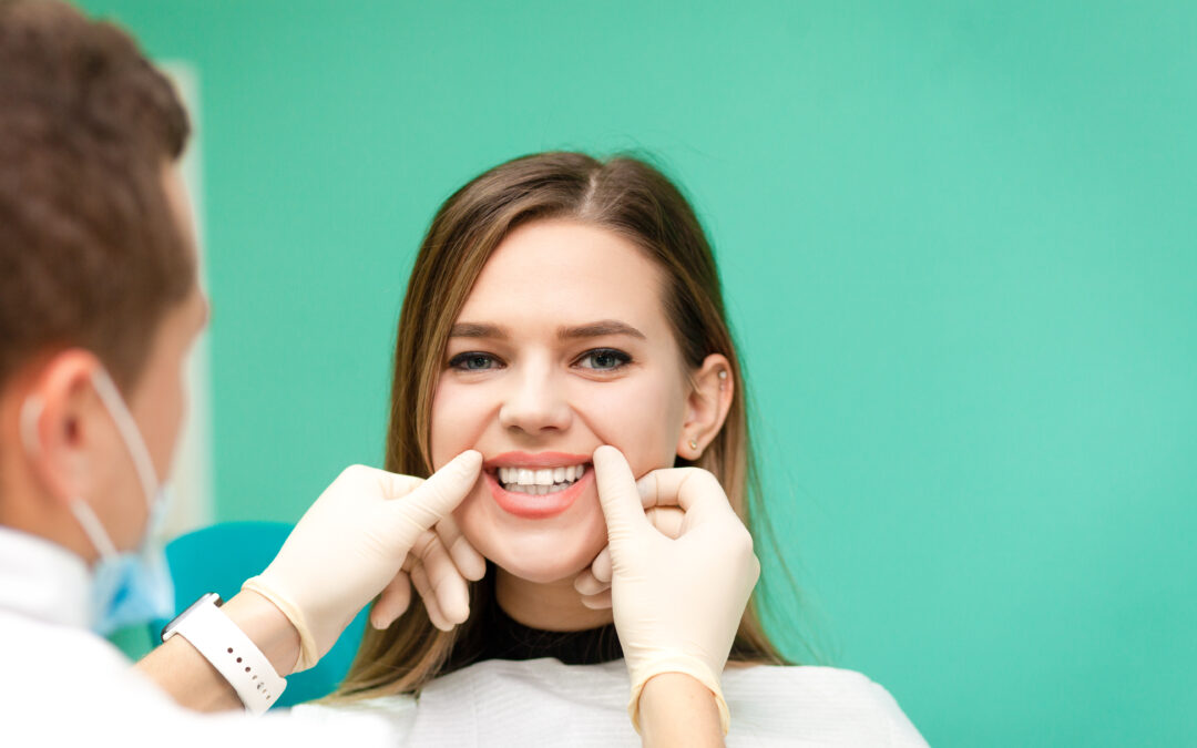 Dental professional wearing gloves pulls the patient’s lips to reveal teeth for examination.